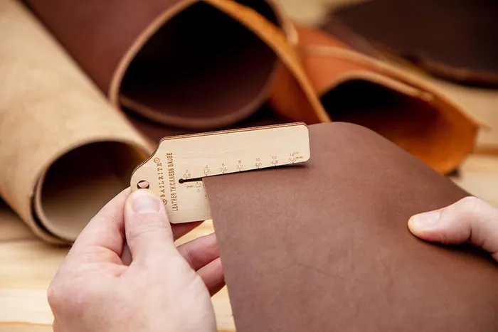 Digital caliper checking a PU leather sample with textile backing during material evaluation