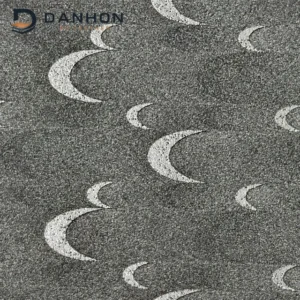 Close-up of dark grey TPU leather material with repeating silver crescent moon motifs and a fine textured surface